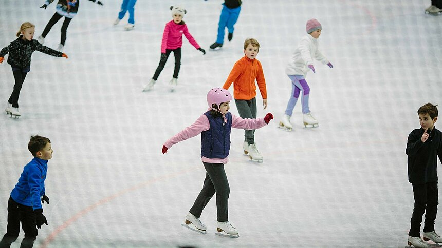 Dzieci jeżdżące na łyżwach na lodowisku